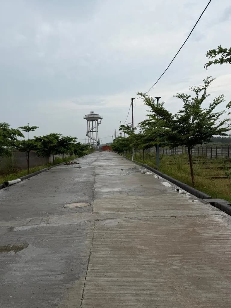 Palm City Haridwar — internal road stretch with the site water tower in the distance